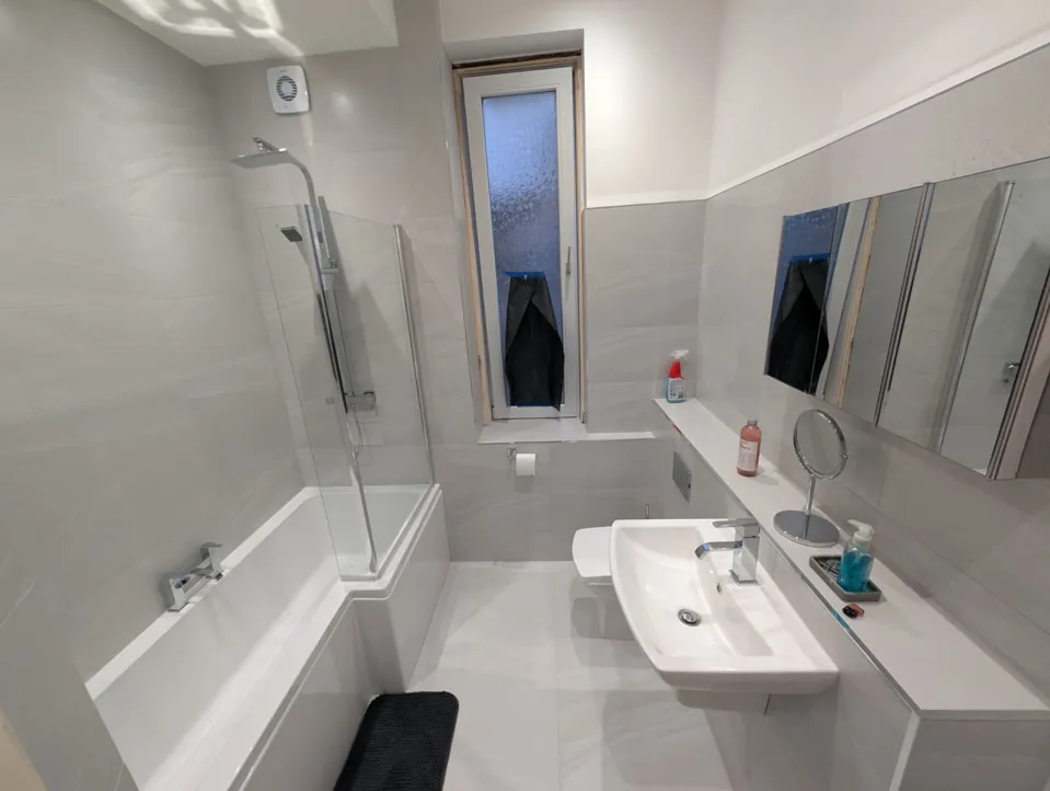 White fitted bath and shower screen with grey walls