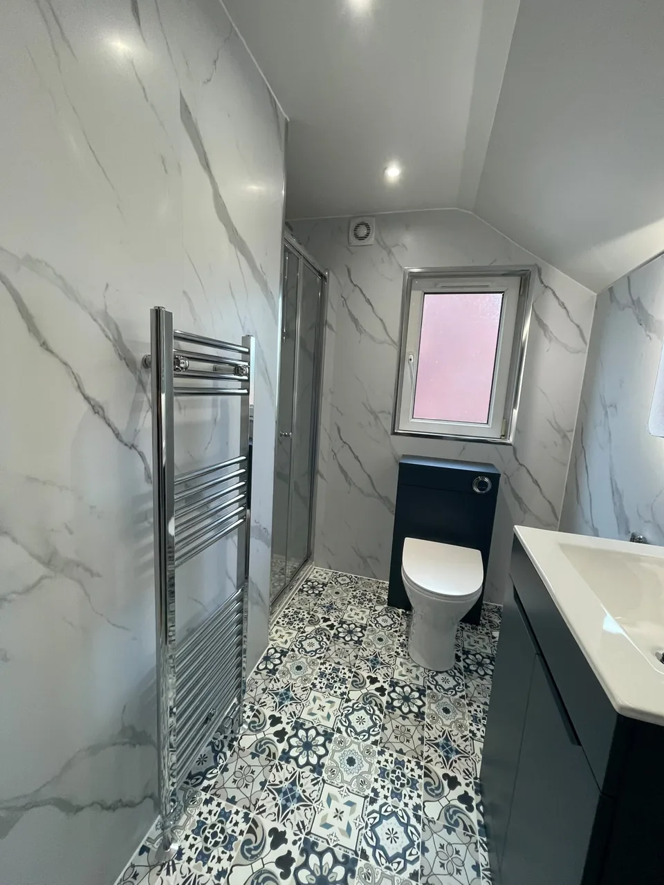 Glass shower enclosure and patterned bathroom flooring