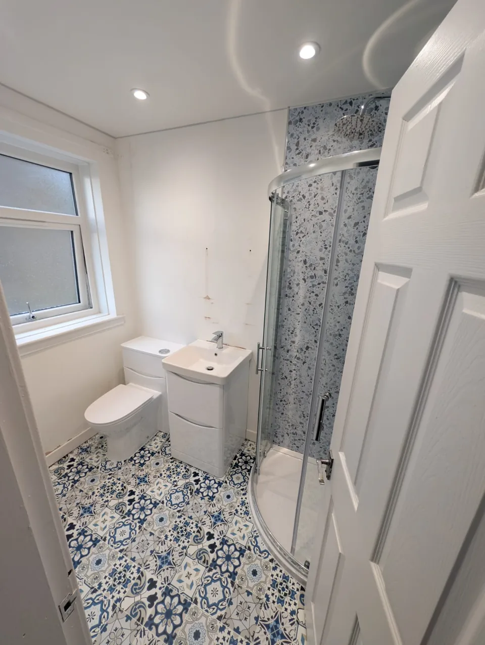 Compact shower room with white vanity and patterned floor